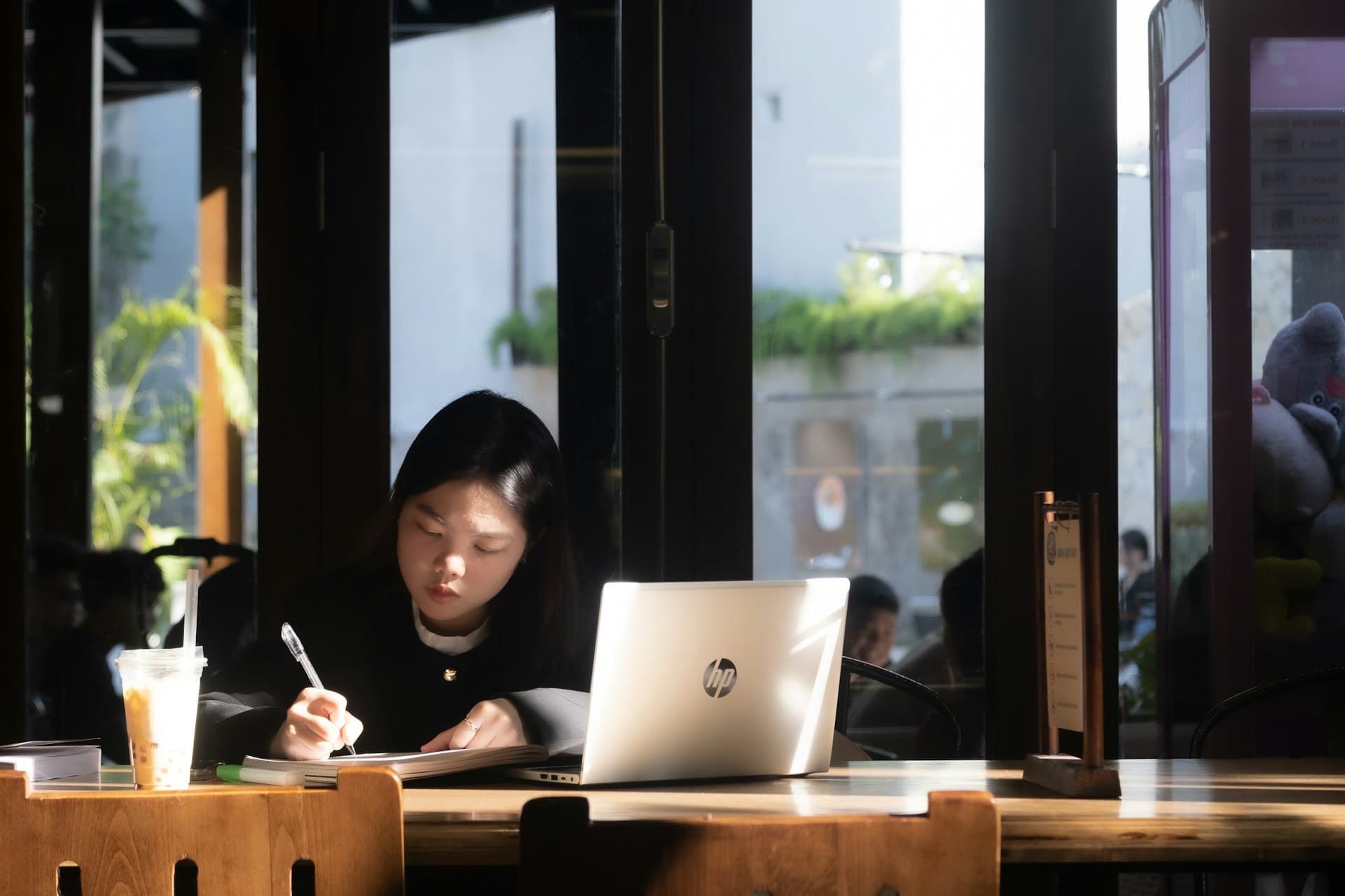 Woman studying at a café with laptop and notebook
